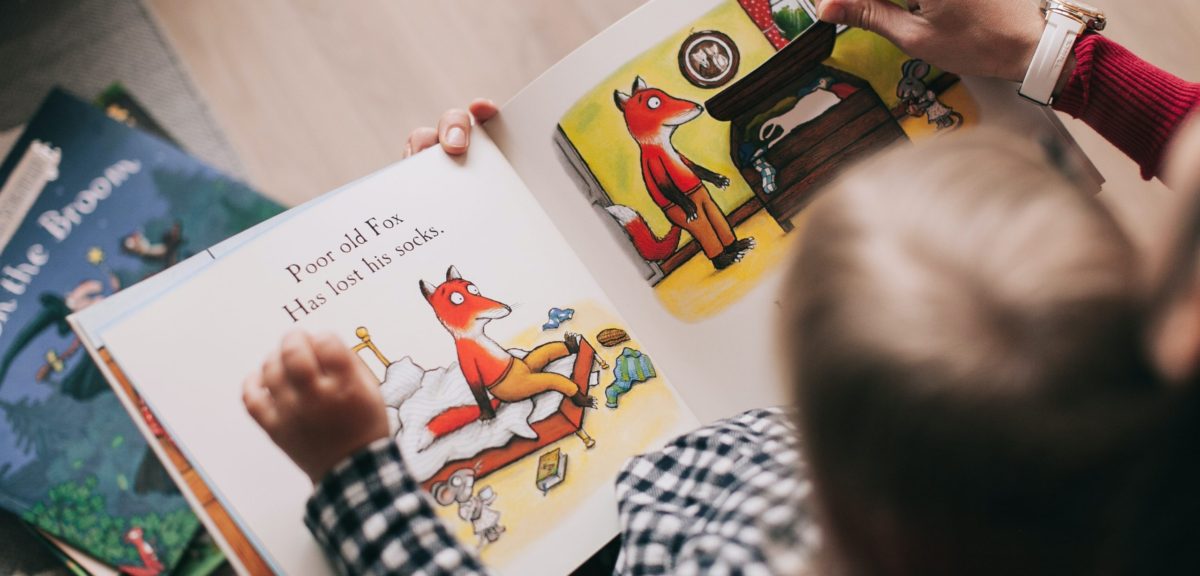 Child reading book with carer generic